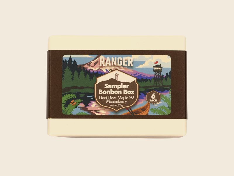 A Ranger Sampler Bonbon Box with a mountain and lookout tower on the label